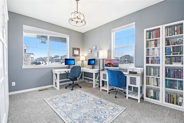 carpeted office space with a healthy amount of sunlight, visible vents, baseboards, and an inviting chandelier