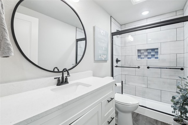 full bath with vanity, wood finished floors, a shower stall, and toilet