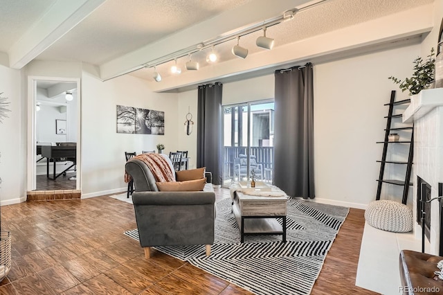 living area with a textured ceiling, beamed ceiling, a fireplace, and baseboards