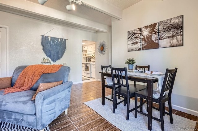 dining space featuring beamed ceiling, wood finished floors, and baseboards