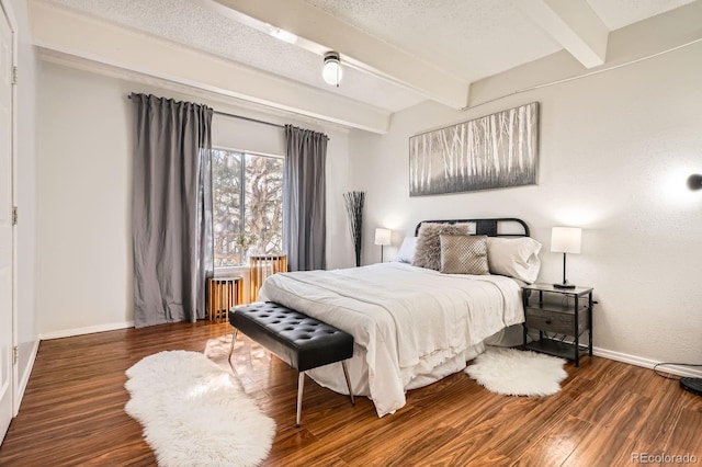 bedroom featuring a textured ceiling, baseboards, beam ceiling, and wood finished floors