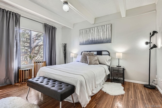 bedroom with baseboards, radiator heating unit, beamed ceiling, wood finished floors, and a textured ceiling