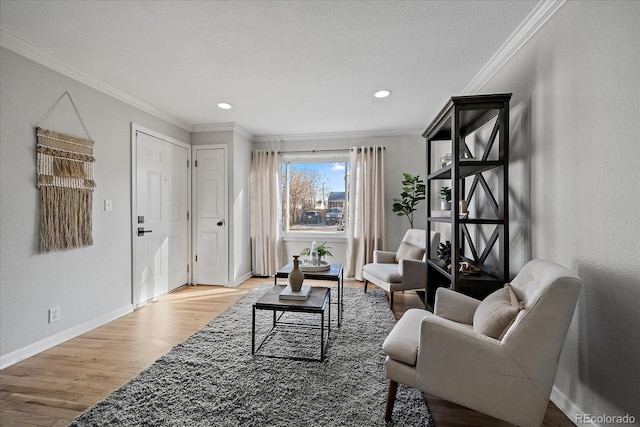 living room featuring ornamental molding, a textured ceiling, wood finished floors, baseboards, and a textured wall