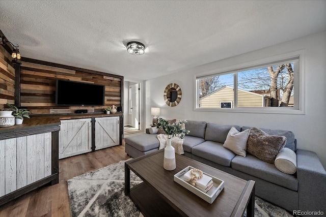 living area with wooden walls, wood finished floors, and a textured ceiling