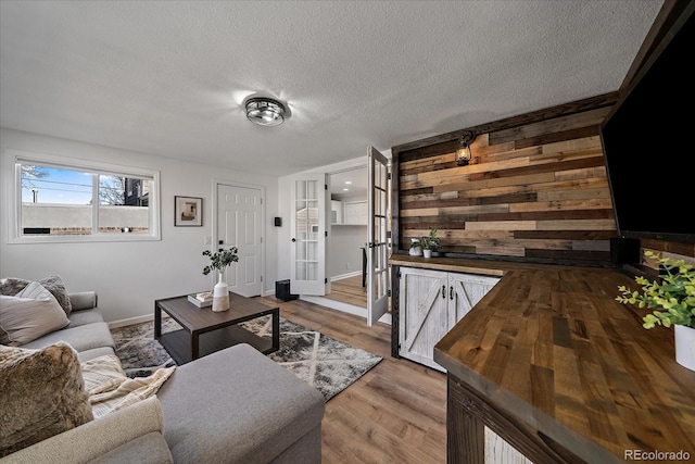 living area with wood finished floors, baseboards, wood walls, and a textured ceiling