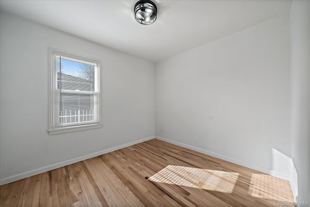 spare room featuring baseboards and wood finished floors