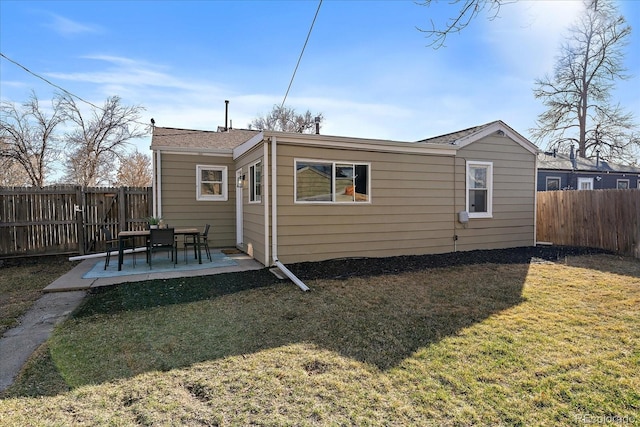 rear view of house with a patio, a yard, and a fenced backyard