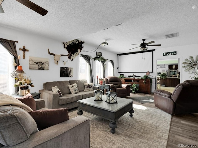 living room with hardwood / wood-style flooring, ceiling fan, and a textured ceiling