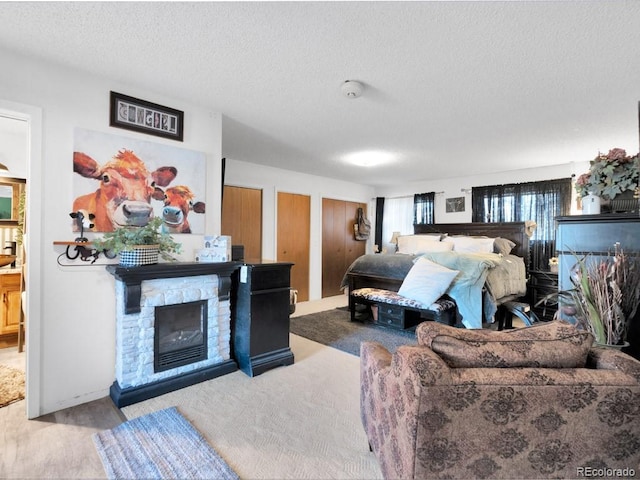 317 Adams Ave, Akron, CO 80720 - bedroom with light wood-type flooring, a textured ceiling, and a fireplace