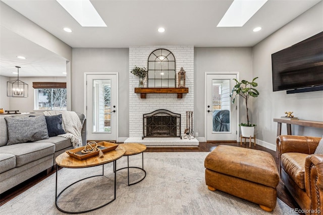 living room with hardwood / wood-style flooring, a notable chandelier, and a brick fireplace