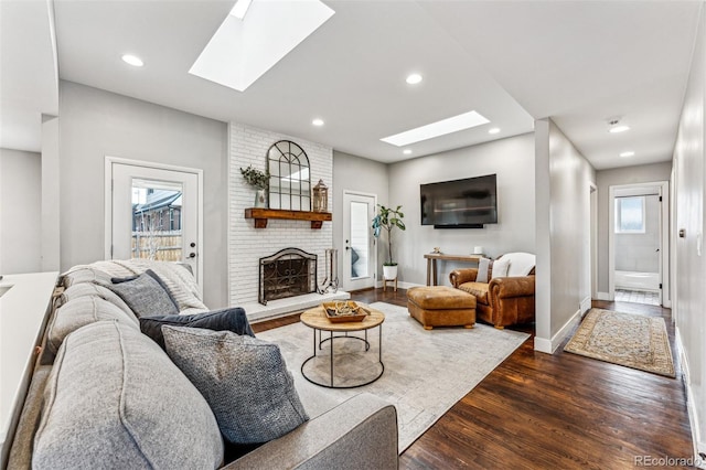 living room with a fireplace, dark hardwood / wood-style flooring, and a skylight