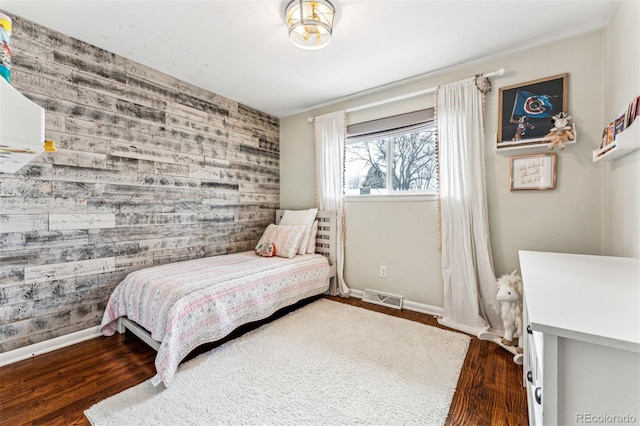 bedroom with dark hardwood / wood-style flooring and wood walls