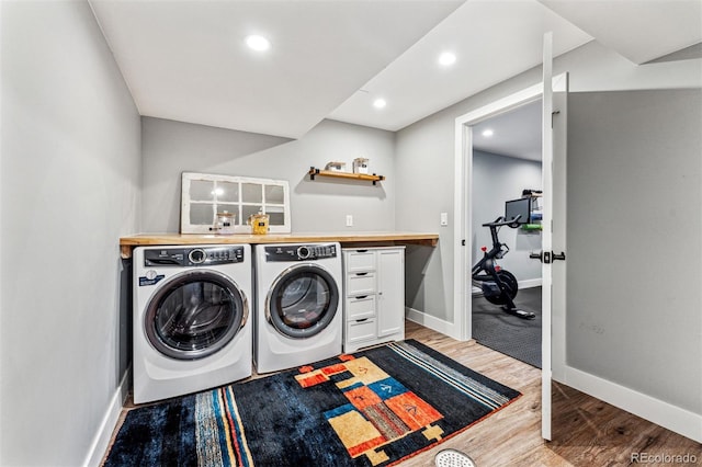 clothes washing area with washer and dryer and light hardwood / wood-style floors