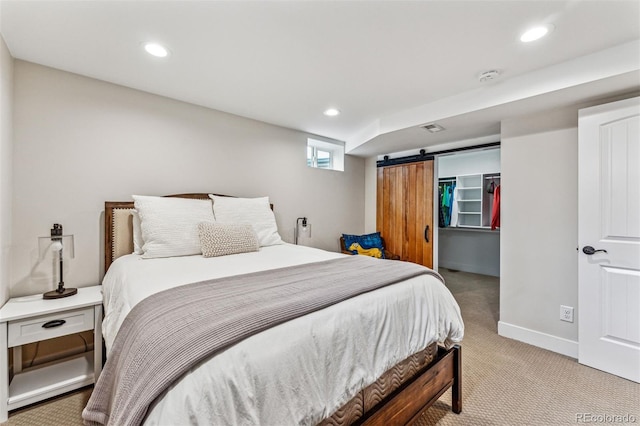 carpeted bedroom with a walk in closet, a barn door, and a closet