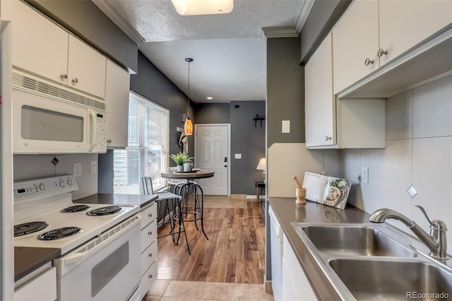 kitchen with white appliances, white cabinetry, and sink