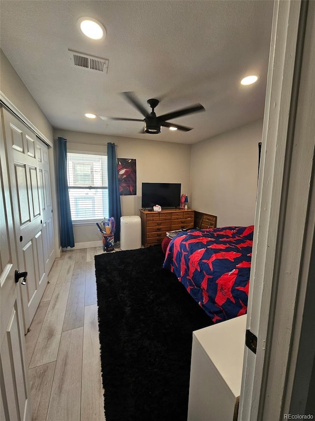 bedroom featuring a ceiling fan, visible vents, recessed lighting, light wood-style floors, and a textured ceiling