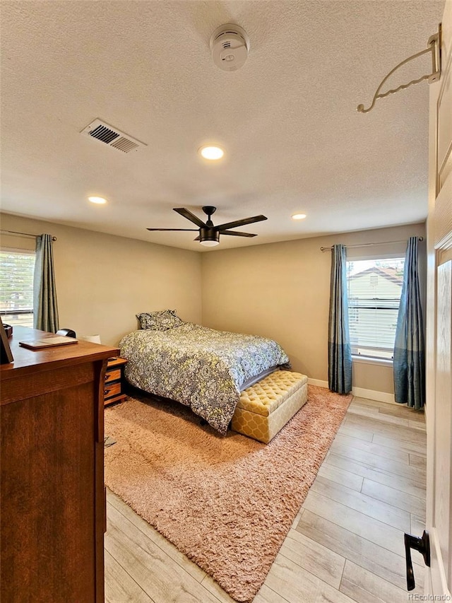 bedroom featuring recessed lighting, visible vents, light wood finished floors, and a textured ceiling