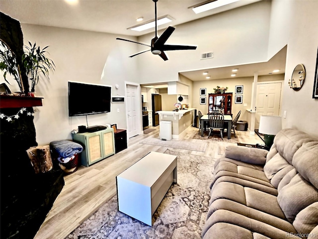 living room with visible vents, light wood-style flooring, high vaulted ceiling, and ceiling fan