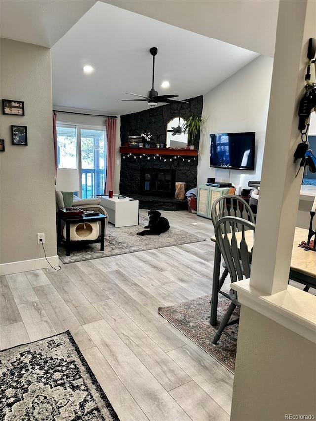 living room with baseboards, ceiling fan, a stone fireplace, recessed lighting, and wood finished floors