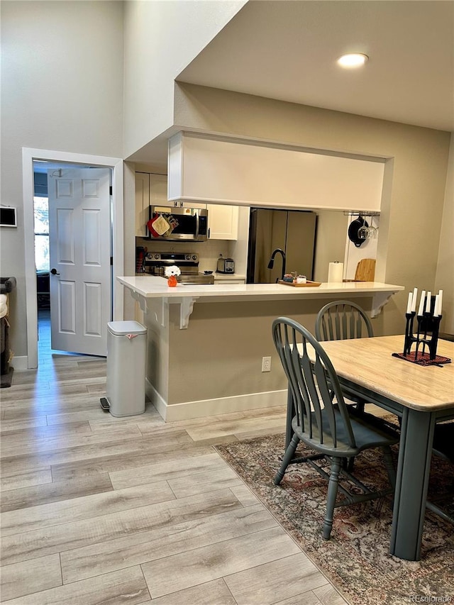 dining area featuring baseboards and light wood-type flooring