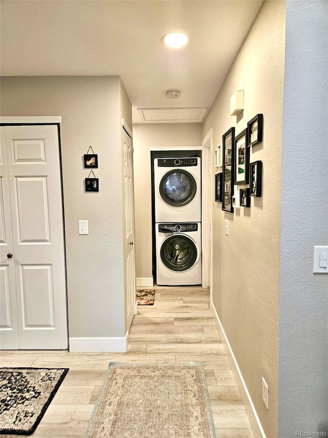 hallway featuring stacked washer / dryer, baseboards, and wood finish floors