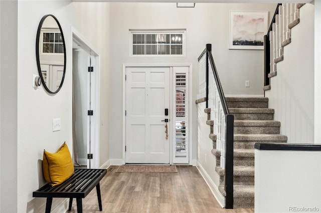 foyer entrance with stairway, baseboards, and wood finished floors
