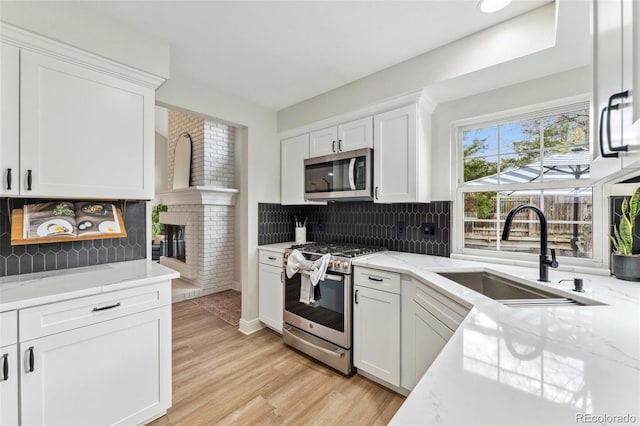 kitchen featuring white cabinetry, stainless steel appliances, tasteful backsplash, and a sink