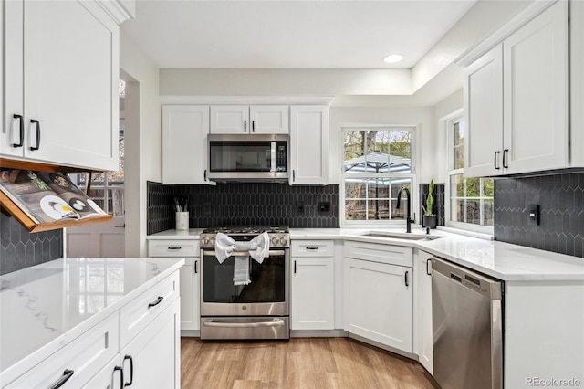 kitchen featuring tasteful backsplash, appliances with stainless steel finishes, a sink, and white cabinets