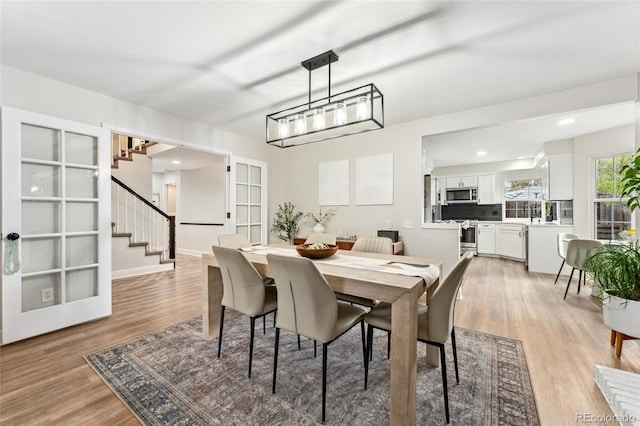 dining room featuring recessed lighting, light wood-style flooring, and stairs