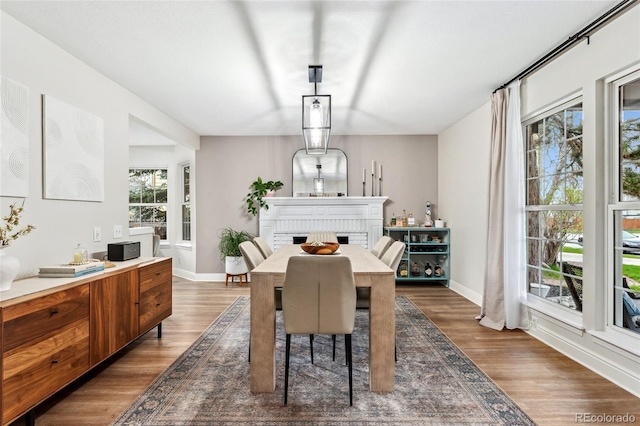 dining space featuring baseboards, a brick fireplace, and dark wood-style floors
