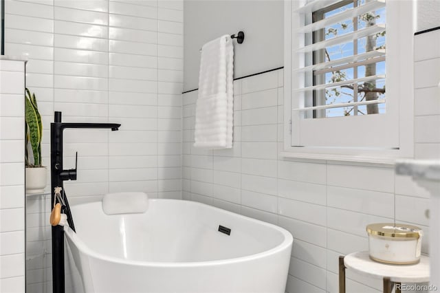 bathroom with a soaking tub and tile walls
