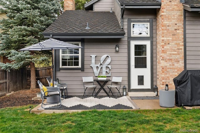 back of house featuring a shingled roof, a chimney, and fence