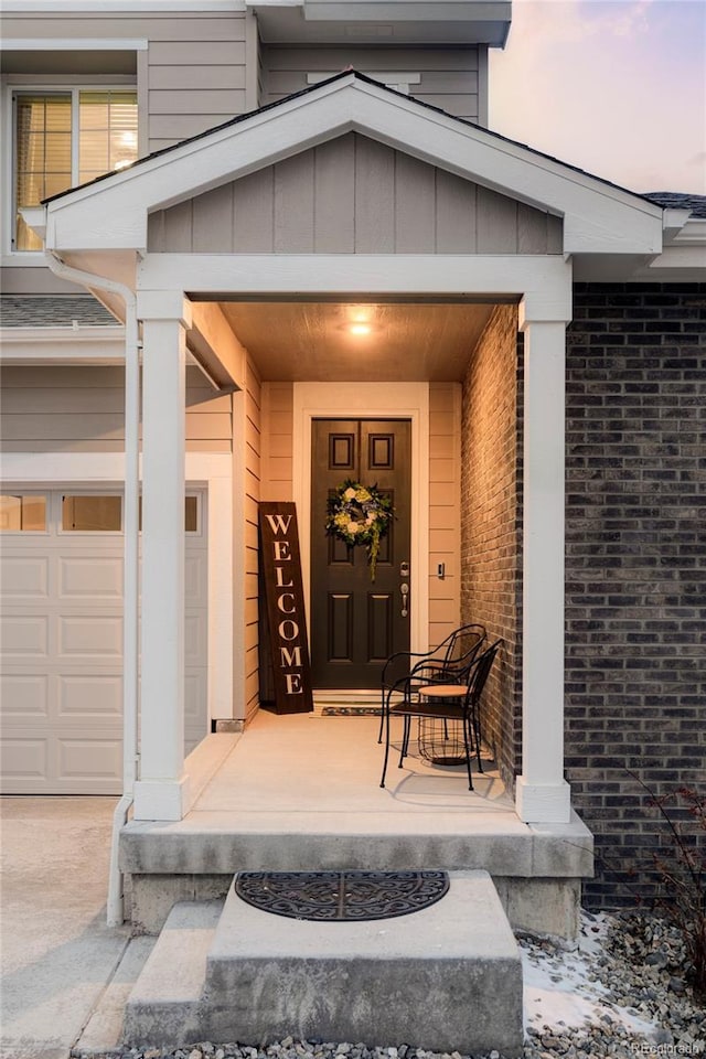 property entrance featuring a porch, brick siding, and a garage