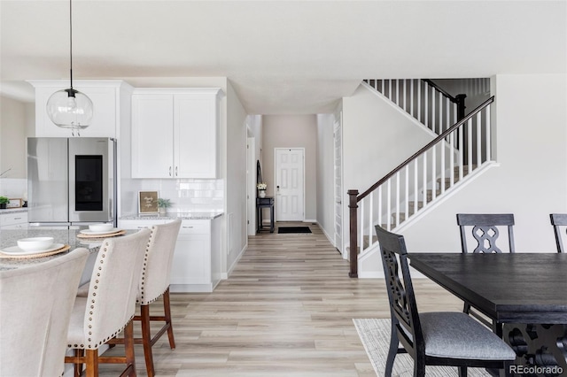 kitchen featuring light wood-style flooring, white cabinets, hanging light fixtures, backsplash, and smart refrigerator