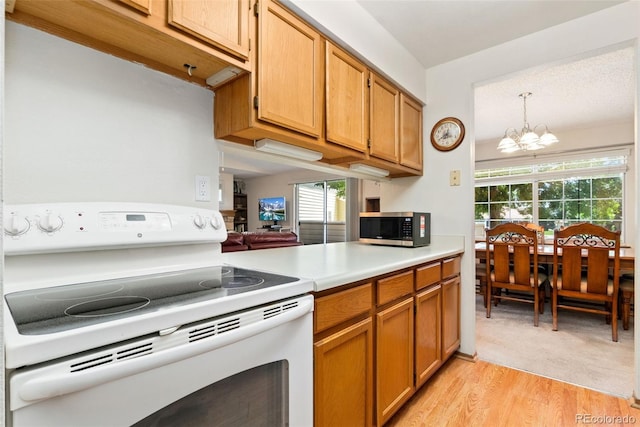 8404 Everett Way Unit A, Arvada, CO 80005 - kitchen featuring white range with electric stovetop, stainless steel microwave, a chandelier, light countertops, and light wood-type flooring
