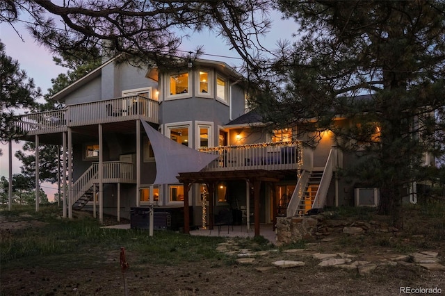 back house at dusk featuring a patio and a deck