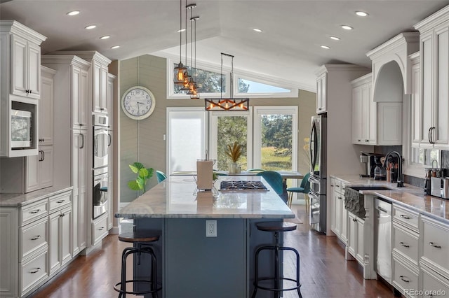 kitchen with pendant lighting, a center island, dark wood-type flooring, vaulted ceiling, and a kitchen breakfast bar