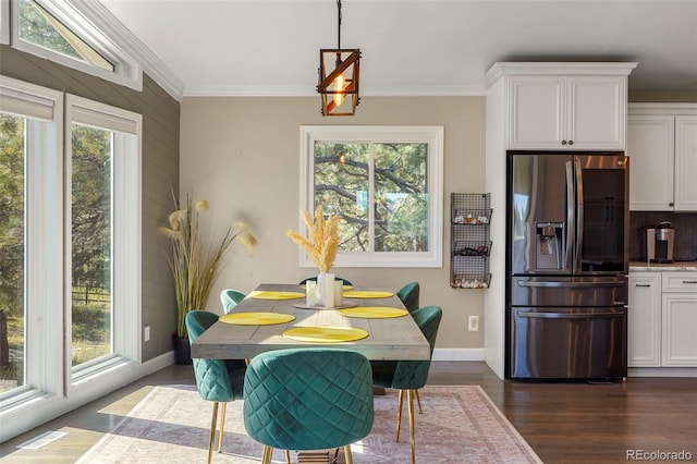 dining space with dark wood-type flooring and crown molding