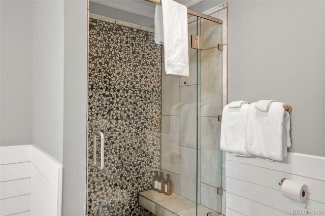 bathroom with a shower with door and crown molding