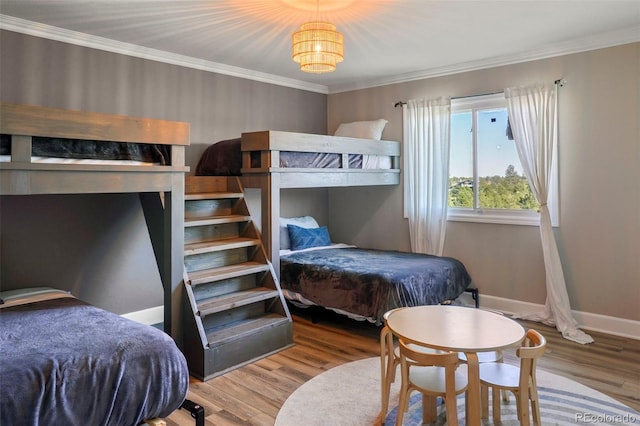 bedroom with wood-type flooring, an inviting chandelier, and ornamental molding