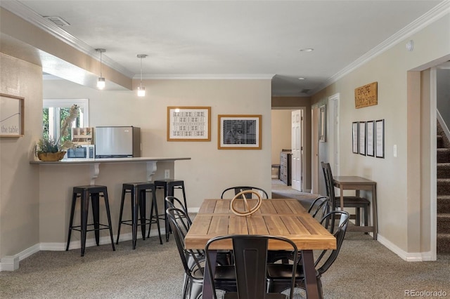 dining area with ornamental molding and light colored carpet