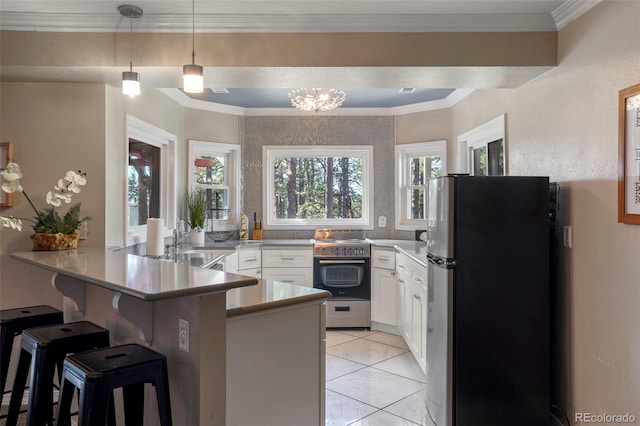 kitchen with appliances with stainless steel finishes, hanging light fixtures, a kitchen breakfast bar, white cabinetry, and kitchen peninsula