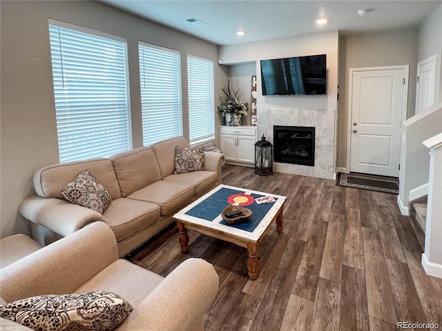 living room featuring a tile fireplace and dark wood-type flooring