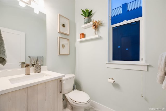 bathroom featuring vanity, toilet, and baseboards