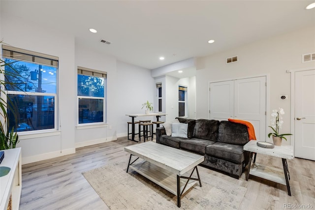 living area featuring light wood-style floors, baseboards, visible vents, and recessed lighting