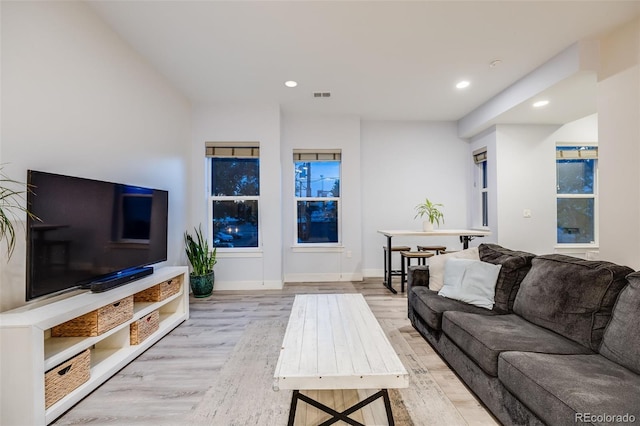 living room with recessed lighting, visible vents, light wood-style flooring, and baseboards