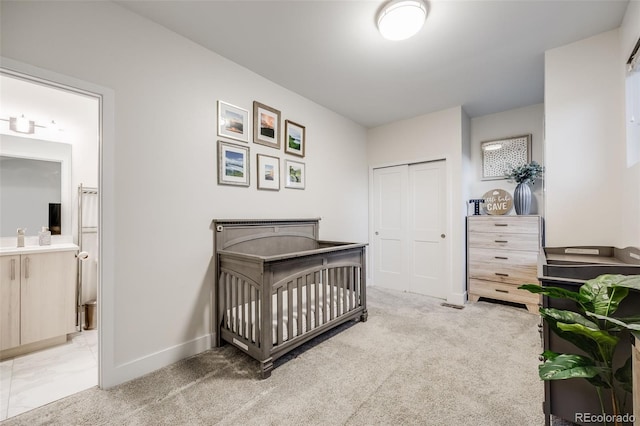 bedroom with light carpet, connected bathroom, baseboards, and a closet