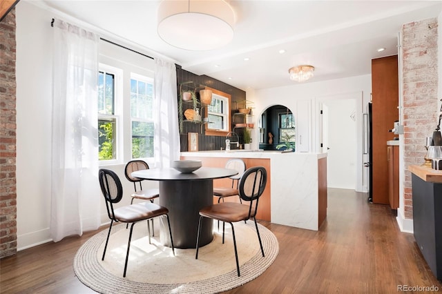 dining area with brick wall and hardwood / wood-style floors