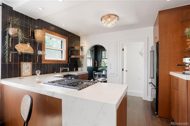 kitchen with high quality fridge, stainless steel gas stovetop, dark hardwood / wood-style floors, and kitchen peninsula