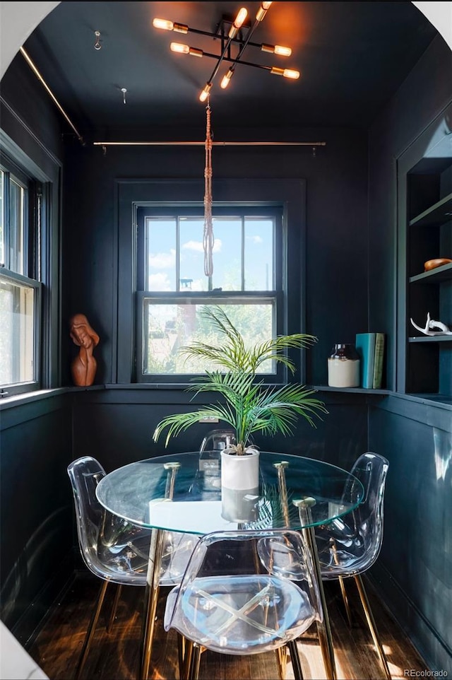 dining room featuring built in shelves, a chandelier, and hardwood / wood-style floors